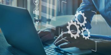 manos escribiendo en un computador y símbolos de Digitalización y Automatización de Procesos